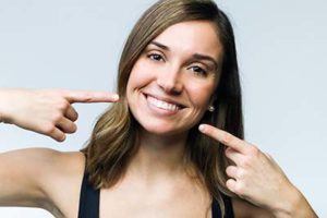 A woman points to her smile after getting cosmetic dentistry in Gulfgate, TX