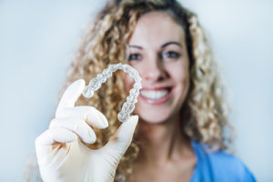 a dentist holds out aligners as she explains teeth straightening and invisilign in gulfgate tx