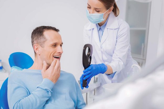 a dentist shows a man his new dental implants